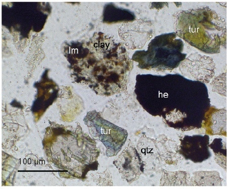 Transmitted light image showing fine haematite (he) & limonite (lm) locked with quartz (qtz), tourmaline (tur) and clay.