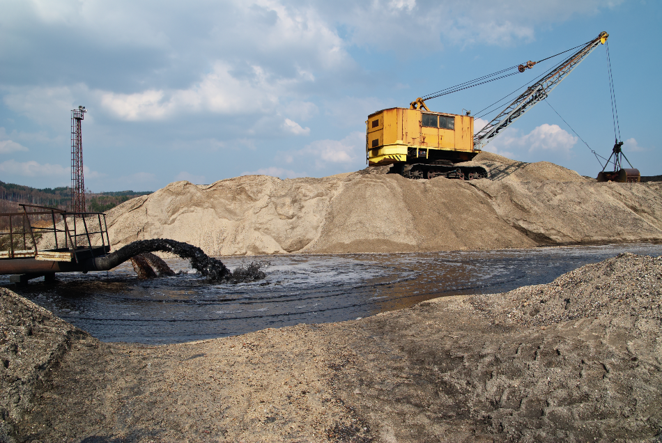 Rope excavator for mining sludge among piles of sand, black sludge polluted water gushing from a pipe, black stream polluted water, environmental pollution